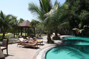 Dos personas sentadas en sillas junto a una piscina en The Fern Sattva Resort, Dwarka en Dwarka