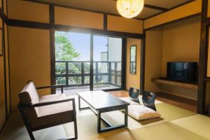 a living room with a table and a tv at 料理の宿　伊豆の花 in Ito