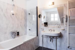 La salle de bains est pourvue d'une baignoire, d'un lavabo et d'une douche. dans l'établissement Hotel Dolomitenhof & Chalet Alte Post, à Sesto