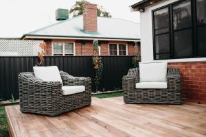 two wicker chairs sitting on a wooden deck at The Settler - Boutique cottage in Dubbo