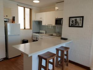 a kitchen with a counter and stools in it at Cappuccino Delight - 1 bedroom central Fremantle apartment in Fremantle