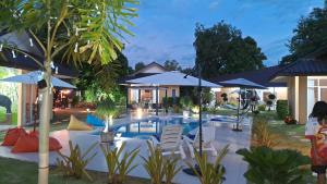 a pool with chairs and umbrellas in a yard at Pool Villa, Resort, Mae Ramphueng Beach, Ban Phe, Rayong, Residence M Thailand in Ban Chamrung