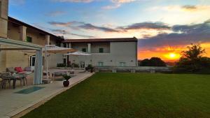 a house with a lawn with a sunset in the background at Hotel Cave Del Sole in Matera