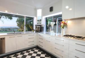 a kitchen with white cabinets and a checkered floor at Out of the Blue I Private Properties in Busselton