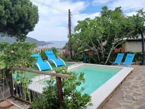 a swimming pool with blue chairs and trees at Villetta dal Ganzetto in Rio Marina
