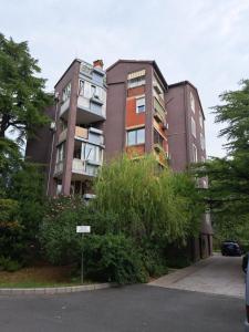 un edificio alto con un árbol delante de él en Koper Apartma, en Koper
