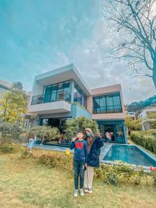 a couple of people standing in front of a house at Villa D’Helen Venus Flamingo Đại Lải in Yen