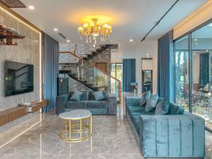 a living room with a blue couch and a chandelier at Villa D’Helen Venus Flamingo Đại Lải in Yen