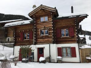 a log house with red doors in the snow at La Demeure des Elfes in Albinen