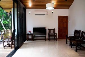 una sala de estar con sillas y un porche con TV. en Zen Forest Entire Villa with Private Pool at Karak, en Kampung Sunjai Gapoi