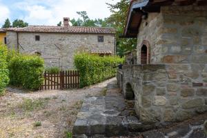 un ancien bâtiment en pierre avec un portail et une clôture dans l'établissement Il Castello di Mangona, à Barberino di Mugello