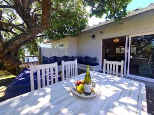 a bottle of wine and a bowl of fruit on a table at Victoria's Place in Kenton on Sea