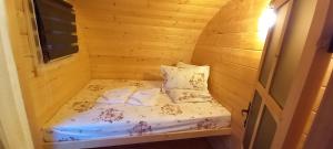 a small bed in a wooden room with a window at La Casute in Apuseni in Gârda de Sus