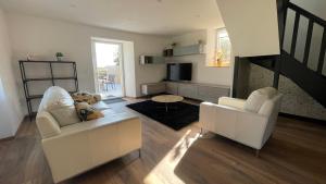a living room with two white chairs and a staircase at Maison bretonne - cottage in Lézardrieux