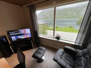 a living room with a large window and a television at Old fisherman's house with 4 bedroom in Gryllefjord
