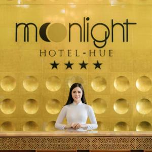 una donna in piedi davanti a un bancone di fronte a un hotel morriott di Moonlight Hotel Hue a Hue