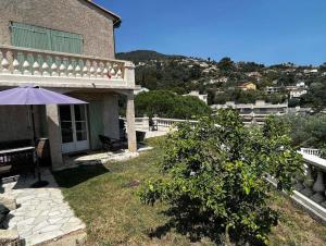 マンドリュー・ラ・ナプールにあるAppartement en Rez de Villa Beausiteの庭のテーブルと傘を持つ家