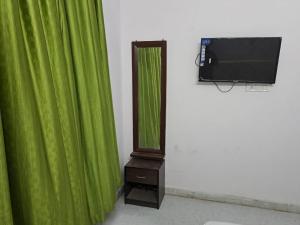 a clock next to a green curtain and a television at Shree Krishna Hotel in Udaipur