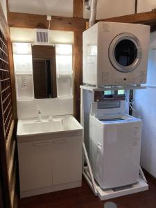 a kitchen with a microwave and a washing machine at ＰＥＮＳＩＯＮ　ＳＨＩＭＡＫＡＺＥ in Motobu