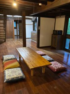 uma sala de estar com uma mesa de madeira e algumas almofadas em ＰＥＮＳＩＯＮ　ＳＨＩＭＡＫＡＺＥ em Motobu