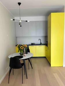 a kitchen with a table and chairs and yellow cabinets at Haki Apartment in Tartu