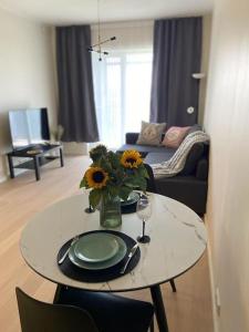 a living room with a table with a vase of sunflowers at Haki Apartment in Tartu +3 photos