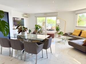 uma sala de estar com uma mesa de vidro e cadeiras em Magnifique 4 pièces avec Terrasse, Piscine em Mandelieu-la-Napoule