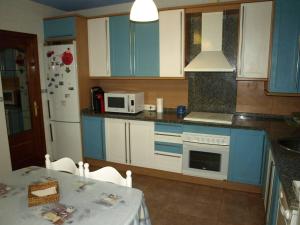 une cuisine avec des placards bleus, une table et un four micro-ondes dans l'établissement ¡¡ Una casa pensada para evadirse y disfrutar !!, à Batres