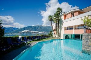 a swimming pool in front of a building with chairs at Bellavista Swiss Quality Hotel in Vira