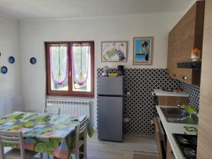 cocina con nevera y mesa con sillas en Appartamento in villa a 20 min da Levanto e dalle 5 Terre-Sesta Godano en Sesta Godano