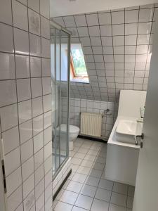 uma casa de banho com azulejos brancos, um WC e uma janela. em Monteurwohnungen Visselhövede em Visselhövede