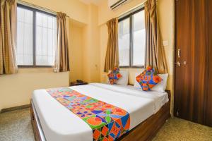 a bedroom with a large bed with colorful pillows at FabHotel Mountain High Inn in Pune