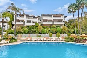 un hotel con piscina frente a un edificio en El Lago de Los Arqueros 2 bedrooms penthouse en Benahavis en Benahavís