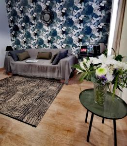 Grand Hôtel Brive في بريف لا غايلارد: غرفة معيشة مع أريكة وطاولة مع زهور