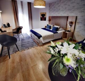 una habitación de hotel con una cama y un jarrón de flores en Grand Hôtel Brive en Brive-la-Gaillarde