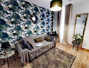 a living room with a couch and a floral wall at Grand Hôtel Brive in Brive-la-Gaillarde