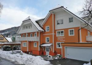 ein großes orangenes Haus mit Garage im Schnee in der Unterkunft Dependance I in Schladming