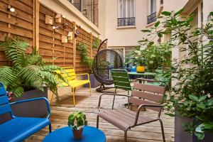 un patio con sedie, tavoli e piante di Hotel Magenta 38 by Happyculture a Parigi