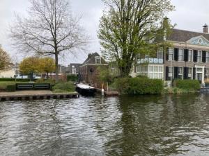 沃爾堡的住宿－Tuinhuis aan het water，一条河,河上有房子和船