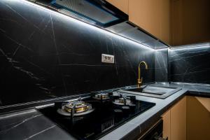 a black kitchen with a stove and a sink at The 502 Mamaia in Mamaia +15 photos