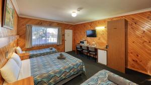 a bedroom with a bed and a desk and a kitchen at Darling River Motel in Bourke