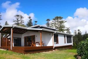 a small white house with a large deck at King Tide House - Ocean Views in Burnt Pine
