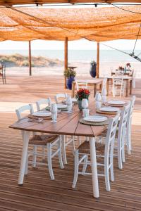 a wooden table with white chairs and a table with the beach at Valerio Resort beach club in Margherita di Savoia