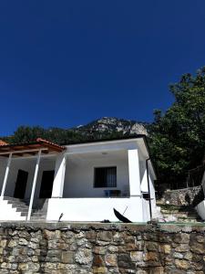 a white house with a stone wall at Guest House Sakollari in Poliçan