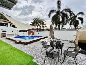 um quintal com uma piscina, uma mesa e cadeiras em Klebang Melaka - ADA villa - 12-15pax/4room/Pool em Malaca