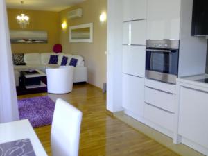 cocina con armarios blancos y sala de estar. en Villa Jelena en Zadar