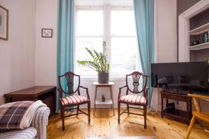 a living room with two chairs and a television at ALTIDO Splendid 2bed apt near Haymarket in Edinburgh