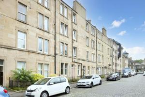 two white cars parked in front of a building at JOIVY Splendid 2bed apt near Haymarket in Edinburgh