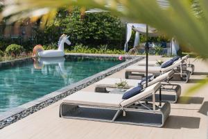a pool with lounge chairs and a swan in the water at Tahagi Villa Tuan Chau Ha Long in Ha Long