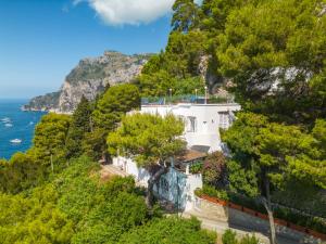 a white house on a hill next to the ocean at Faraglionensis MonaconeHouse Villa in Capri